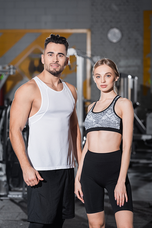 Smiling sportsman  near fit sportswoman in gym