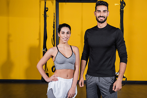 Smiling arabian sportsman  near middle east sportswoman in gym