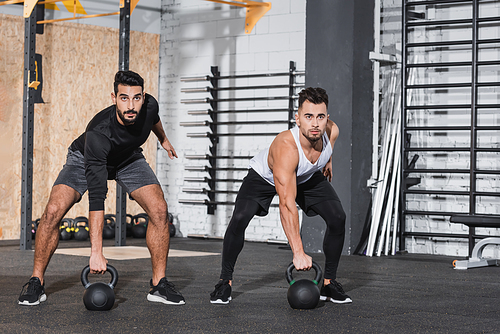 Multiethnic sportsmen training with kettlebells in gym