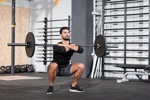 Arabian sportsman lifting barbell in gym