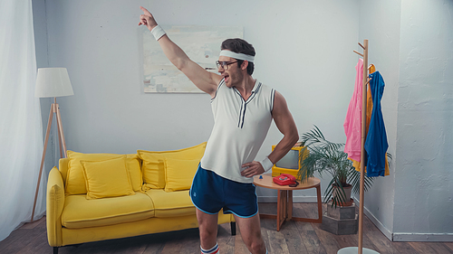 energetic sportsman with hand on hip dancing in living room