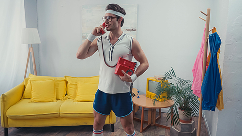 Sportsman standing while talking on landline telephone in living room