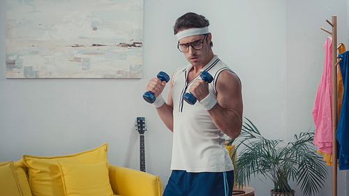 strong man lifting dumbbells in living room, retro sport concept