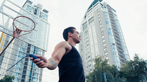 low angle view of bi-racial sportsman training with jump rope outdoors