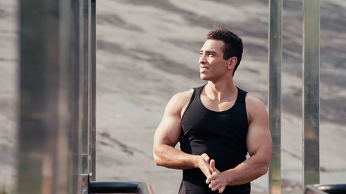 athletic mixed race sportsman looking away at outdoor gym on blurred foreground