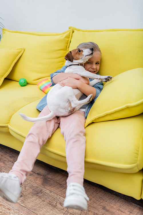 Kid  and hugging jack russell terrier on couch