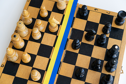 Top view of blue and yellow ribbon on chessboard isolated on white