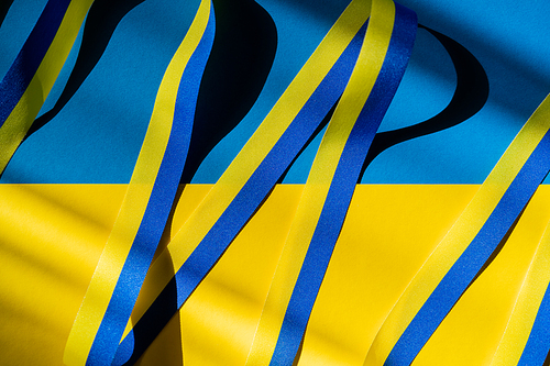 Top view of blue and yellow ribbon with shadow on ukrainian flag