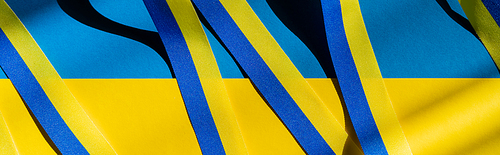 Top view of blue and yellow ribbon with shadow on ukrainian flag, banner