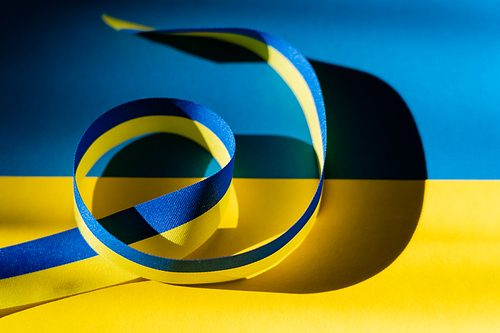 Close up view of blue and yellow ribbon with shadow on ukrainian flag