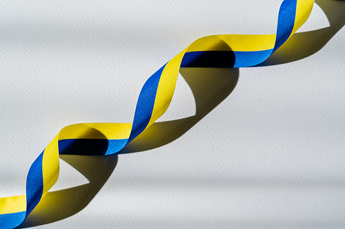 Top view of curly blue and yellow ribbon with shadow on white background