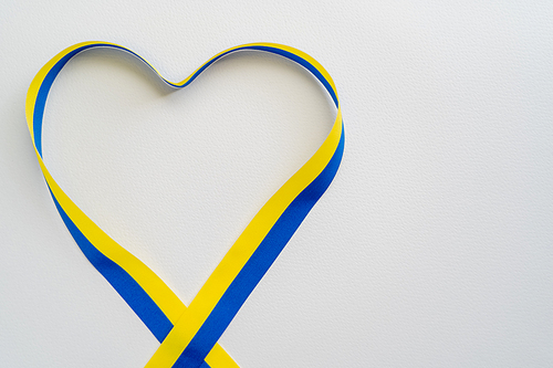 Top view of blue and yellow ribbon in heart shape on white background with copy space