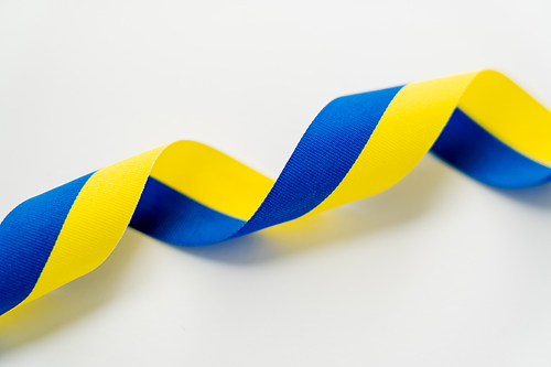 Close up view of curly blue and yellow ribbon on white background