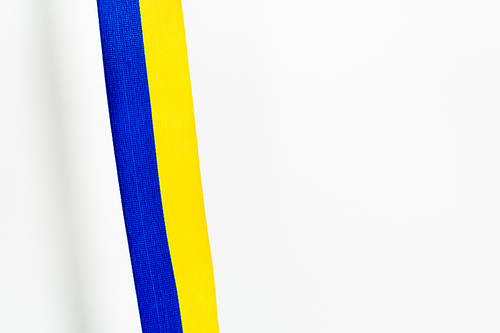 Top view of blue and yellow ribbon with shadow on white background