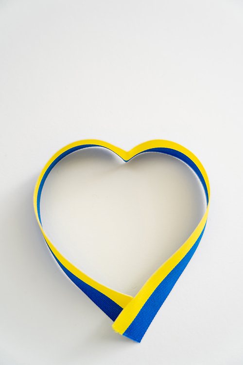 Top view of heart sign from blue and yellow ribbon on white background