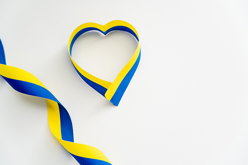 Top view of blue and yellow ribbons in shape of heart symbol on white background