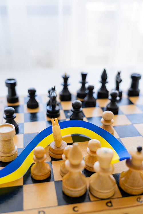 Blue and yellow ribbon on blurred chessboard on white background