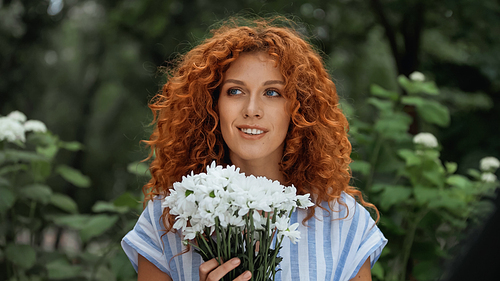 cheerful redhead woman holding bouquet of white flowers