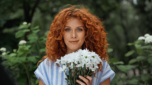 pleased redhead woman holding bouquet of white flowers