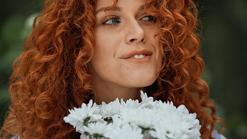close up of happy redhead woman near white flowers