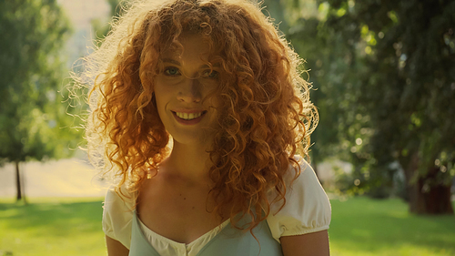 sunshine on curly hair of woman smiling in park