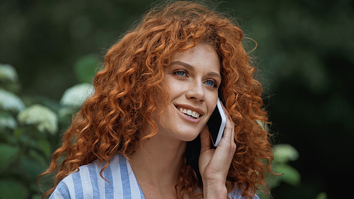 glad young woman with red hair talking on smartphone