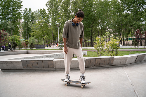 young african american man riding skateboard in park