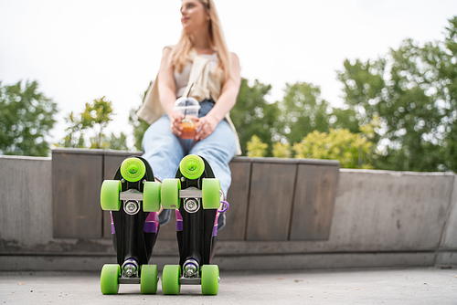 blurred woman in roller skates sitting on border bench outdoors