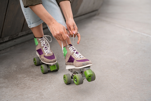 partial view of woman tying laces on roller skate outdoors