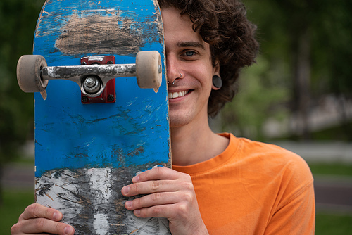 cheerful man  while obscuring face with skateboard