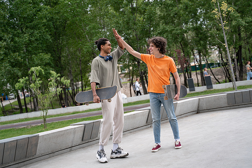 full length view of multiethnic skateboarders giving high five in skate park