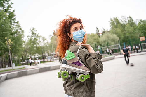 redhead roller skater in medical mask looking away outdoors