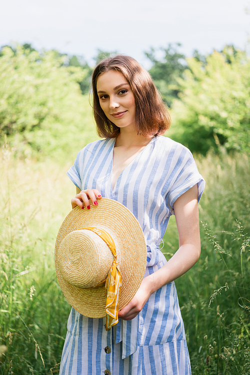 Pretty woman holding sun hat in park during summer