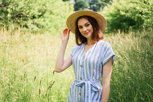 Woman in striped dress holding straw hat in park