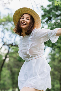 Happy young woman in sun hat standing in park