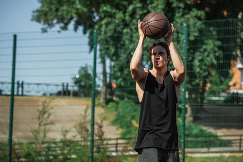 Brunette basketball player holding ball outdoors