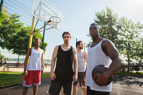 Young interracial men with basketball ball  on playground outdoors