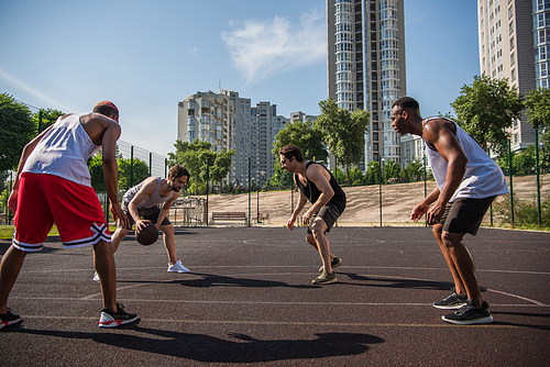 Multiethnic sportsmen playing basketball on playground outdoors