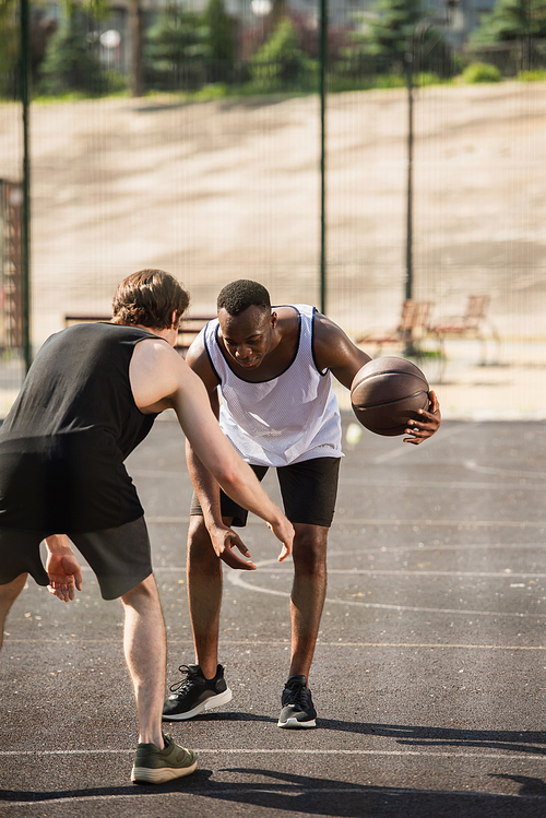 African american man playing basketball with friend on playground