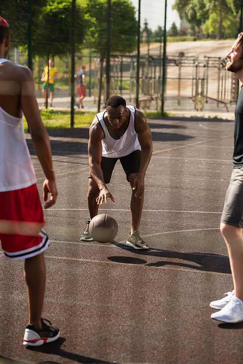 African american man playing basketball near blurred friends outdoors
