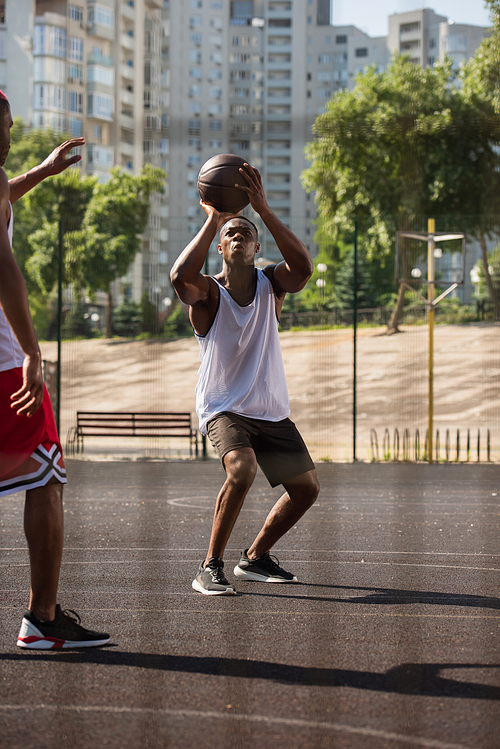 African american man playing basketball near friend on playground outdoors