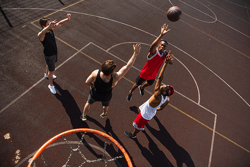 Overhead view of multiethnic sportsmen jumping while playing streetball