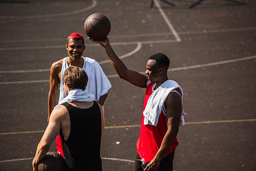 Interracial sportsmen with towels and basketball balls outdoors