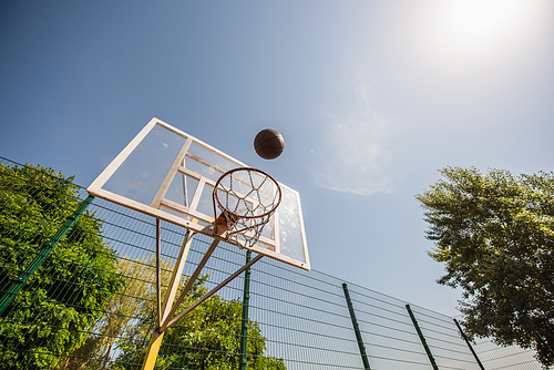 Low angle view of basketball ball near hoop on playground outdoors
