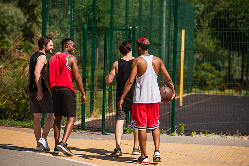 Smiling interracial basketball players walking on playground