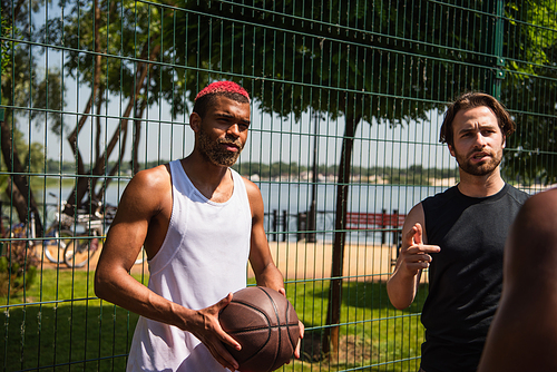 African american basketball player standing near friends talking outdoors