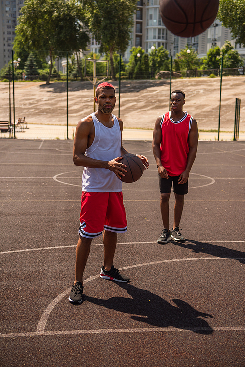 African american sportsmen looking at basketball ball on playground