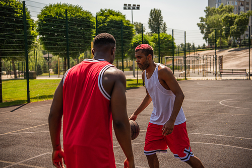 Young african american man playing basketball near friend on outdoor playground