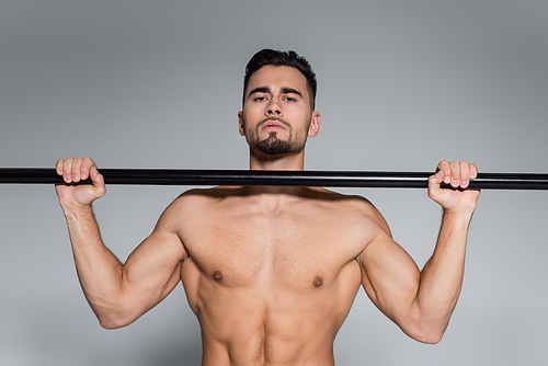 shirtless sportsman exercising on horizontal bar isolated on grey