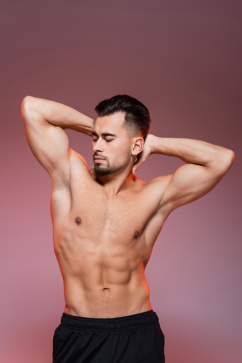 lighting on shirtless man with muscles posing on pink and grey